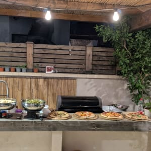שולחן עם פיצות וסלטים תחת פרגולה מעץ