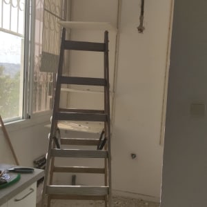 סולם בחדר עם קיר פתוח וחוטי חשמל גלויים