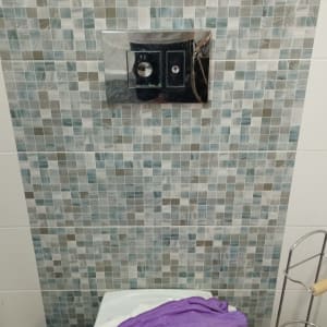 שירותים עם אריחים, מגבת סגולה וחפצים על המדף