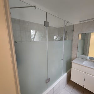 מקלחון זכוכית עם דלתות חלביות בחדר אמבטיה