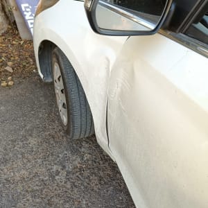 נזק לרכב לבן עם שריטות ופגיעות בצד