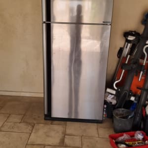 מקרר עומד ליד כלי עבודה וארגז כלים