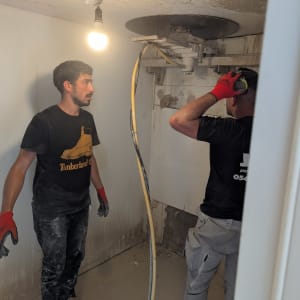 שני אנשים עובדים בחדר עם מכונת ניסור בטון