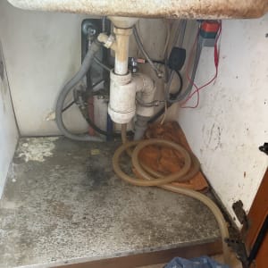 כיור עם צנרת וכלים מתחת לכיור במטבח