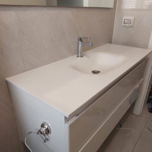 כיור לבן עם ברז על רקע שיש בהיר