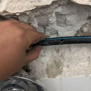 יד מחזיקה צינור ליד קיר שבור