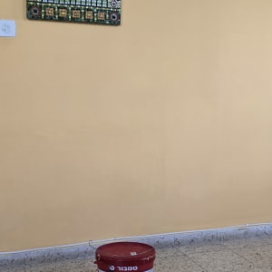 דלי צבע אדום על רצפה ליד קיר צבוע