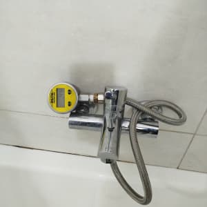 מד לחץ מים מחובר לברז בחדר אמבטיה