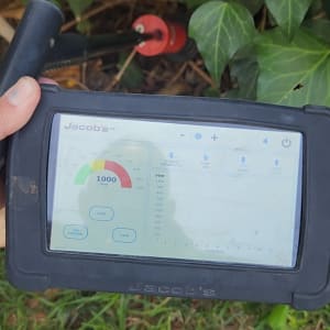 מכשיר מדידה עם מסך תצוגה ליד צמחייה