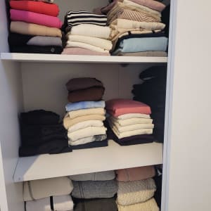 בגדים מקופלים ומסודרים בארון לבן עם מדפים