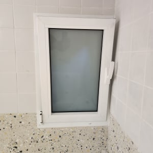 חלון אלומיניום עם זכוכית חלבית על קיר מרוצף