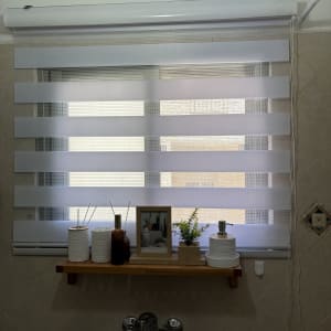 מדף עם קישוטים מעל כיור וחלון עם וילון