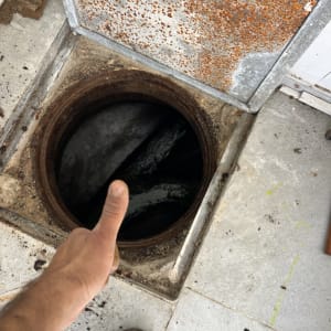 אדם מצביע על פתח ביוב פתוח עם מכסה חלוד