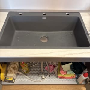 כיור מטבח עם כלים וחומרי ניקוי מתחת