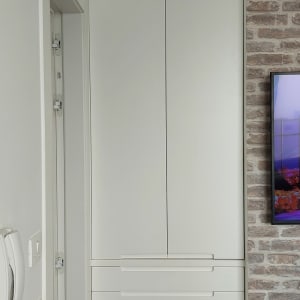 ארון לבן עם דלתות ומגירות ליד קיר לבנים