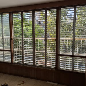 תריסים לבנים על חלונות גדולים עם מסגרות עץ