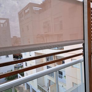 סוכך בד חצי שקוף על מרפסת עם מסגרת עץ