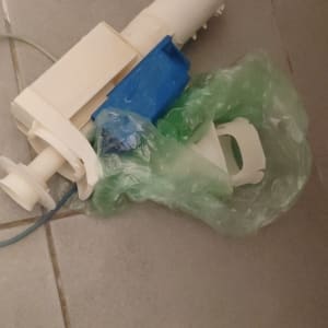 חלק פלסטיק לבן עם רכיב כחול על רצפה אפורה