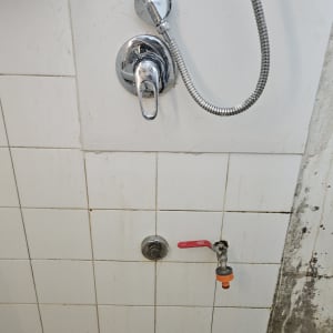 ברזים ומקלחת על קיר אריחים לבנים