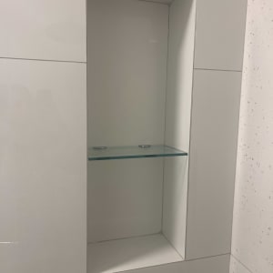 מדף זכוכית בתוך נישה בקיר לבן