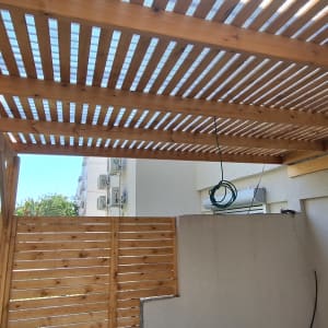 פרגולה מעץ עם גדר עץ בחצר