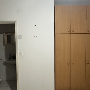 ארון עץ ליד קיר עם חורים, חדר אמבטיה ברקע