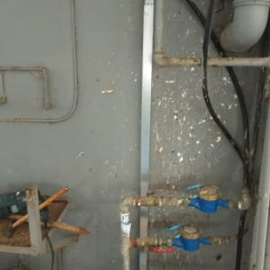 צינורות ומדי מים על קיר עם כבלים חשמליים