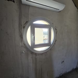 חלון עגול מאלומיניום בקיר בטון חשוף