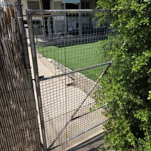 שער מתכת ליד גינה עם דשא סינתטי