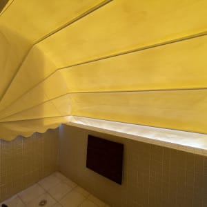 סוכך צהוב נפתח עם קפלים על קיר מרוצף