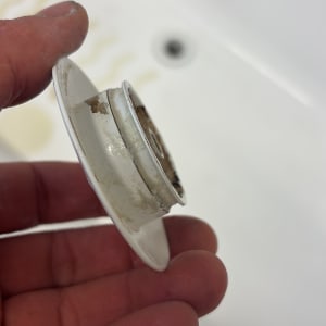 חלק פלסטיק מלוכלך מוחזק ביד ליד כיור