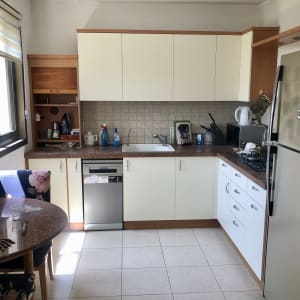 מטבח עם ארונות לבנים, מקרר, כיור ומדיח כלים