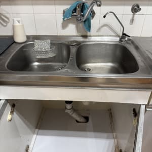 כיור מטבח עם ברזים וצנרת גלויה מתחת