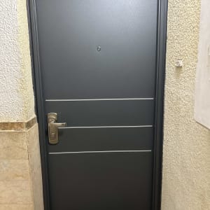 דלת מתכת אפורה עם ידית כסופה ומנעול