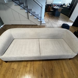 ספה אפורה בחדר עם רצפת עץ וכלי ניקוי ברקע