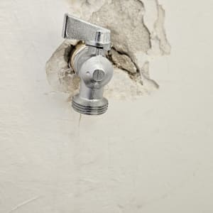 ברז מתכת בקיר עם טיח מתקלף