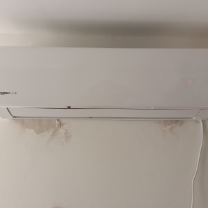 מזגן קיר לבן מותקן על קיר עם חוט חשמל