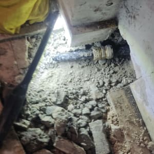 צינור שחור עם מחבר מתכת על רצפה שבורה