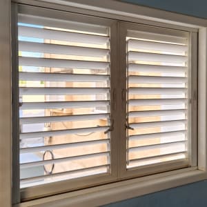 תריסים לבנים פתוחים למחצה בחלון כפול