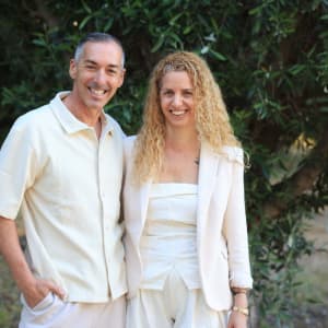 זוג מחייך עומד ליד עץ ירוק