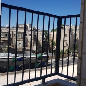 מעקה מתכת שחור במרפסת עם נוף עירוני