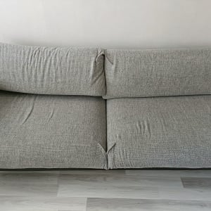 ספה אפורה עם קמטים קלים על הרצפה