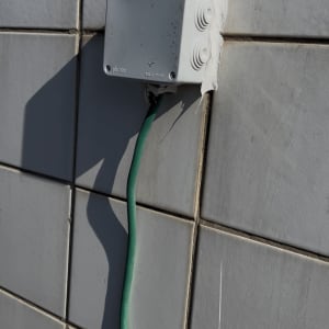 תיבת חיבורים עם כבל ירוק על קיר אריחים