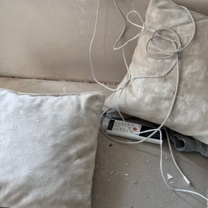 כריות מאובקות על ספה עם כבלים חשמליים