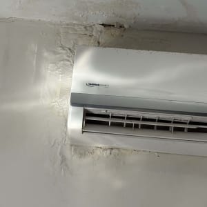 מזגן על קיר עם סימני רטיבות וקילוף צבע