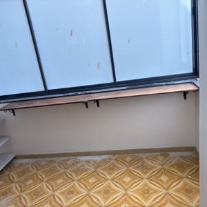 מדף עץ מותקן ליד חלון עם רצפת אריחים דקורטיבית