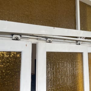 דלתות זכוכית עם מסגרת לבנה ומסילה עליונה