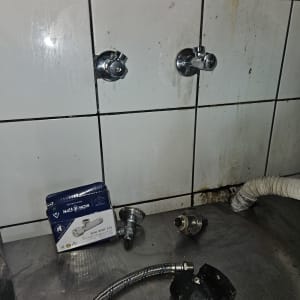 חלקי אינסטלציה על משטח עבודה עם אריחים מלוכלכים