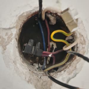 חוטי חשמל צבעוניים בקופסת חיבורים בקיר