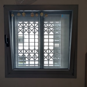 חלון עם תריסים מתכתיים ודמויות קטנות על המסגרת